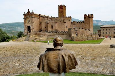 Rear view of man and old building against sky in city