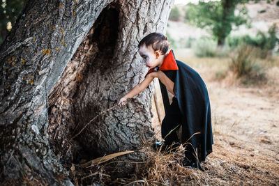 Side view of woman standing on tree trunk