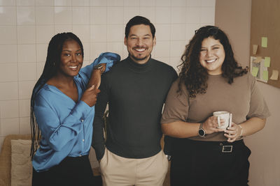 Portrait of smiling friends standing against wall