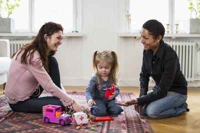 Happy lesbian couple playing with girl at home