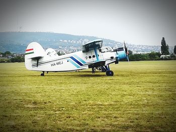 Airplane flying over field against sky