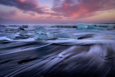 Long exposure of waves in sea against sky during sunset