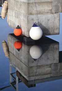 High angle view of buoys hanging by concrete pier with reflection in lake