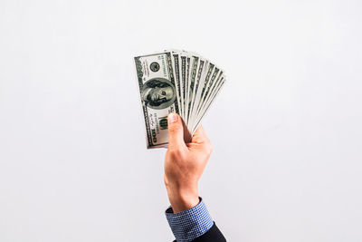 Cropped hand holding paper currency against white background