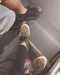 Low section of woman standing on escalator