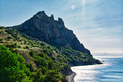 Scenic view of sea by mountains against sky