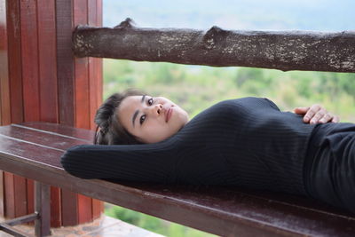 Portrait of young woman lying down on bench