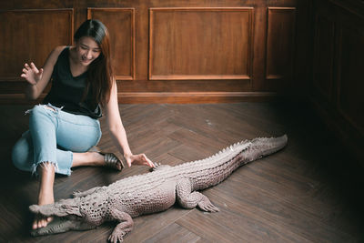 Young woman sitting by crocodile statue on floor