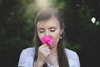 Portrait of beautiful woman holding red flowering plant