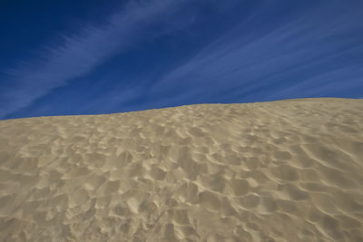 Sand dune in desert against blue sky