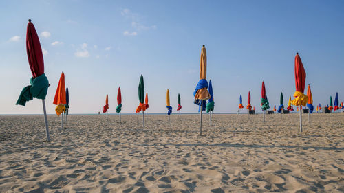 Panoramic view of parasols at beach against sky