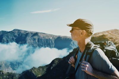 Mature man looking at mountains against sky during sunny day