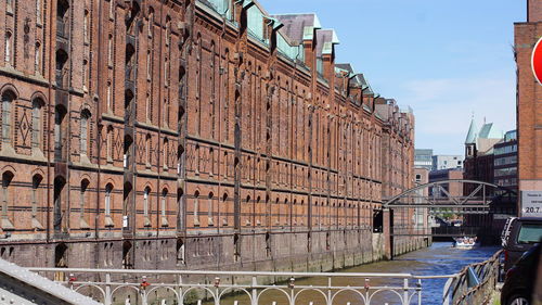 Bridge over canal by buildings against sky