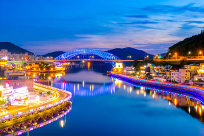 Illuminated bridge over river against sky at night