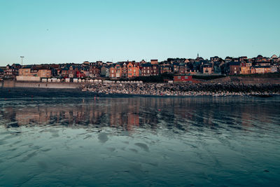 Buildings reflecting in water during sunset.