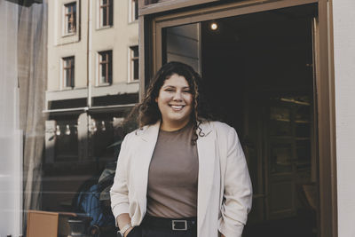 Portrait of smiling female business professional near office doorway