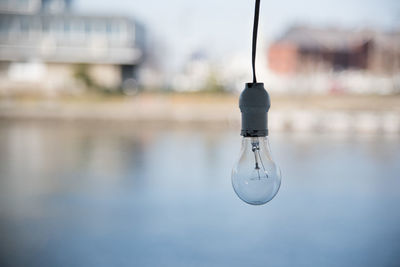 Close-up of light bulb against river