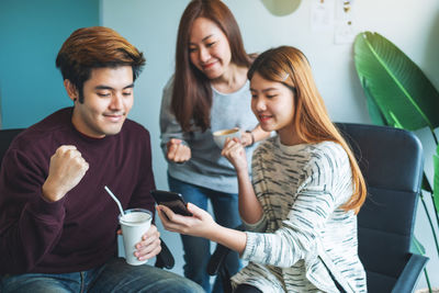 A group of young people having fun and celebrating while watching on mobile phone together