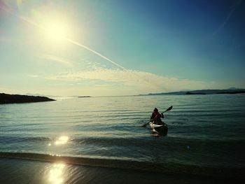 Silhouette person on sea against sky
