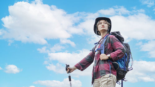 Low angle view of woman looking away against sky