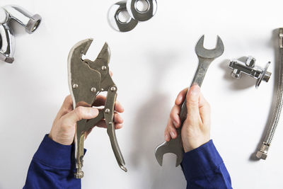 Cropped hands of man holding hand tools on white table