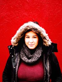 Portrait of smiling woman in warm clothes against red background