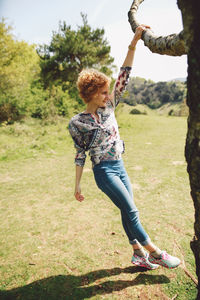 Full length of young woman standing by tree at park