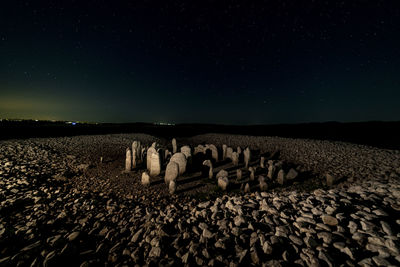 Stones on field against clear sky at night