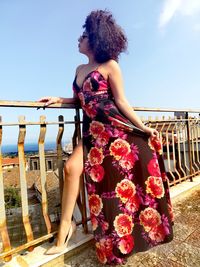 Woman standing by railing against sky