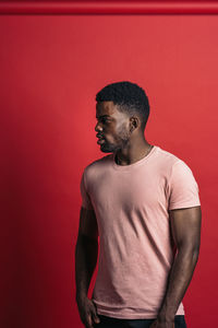 Young man looking away against red background