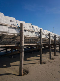 Abandoned wooden structure on beach against clear blue sky