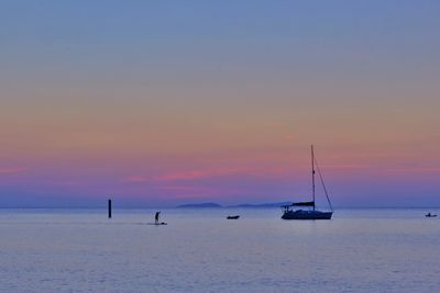 Sailboats in sea against sky during sunset