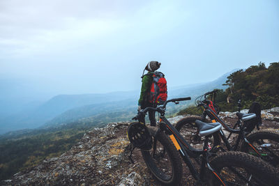 Rear view of people riding motorcycle on mountain against sky