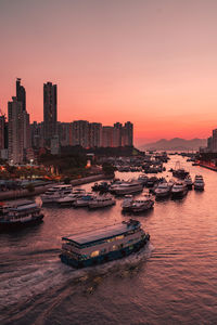 Aerial view of buildings by sea against sky during sunset