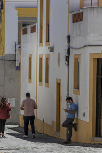 Rear view of people walking on street amidst buildings