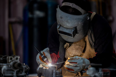 Welder in face mask welds with argon arc stainless steel welding, industrial worker at the factory.