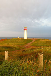 Lighthouse on grassy field by sea