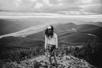 Rear view of girl standing on mountain against sky