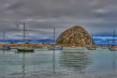 Sailboats moored in sea against sky