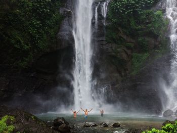 People waving at waterfall