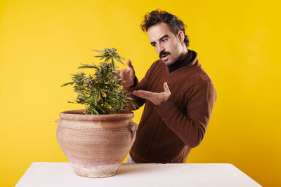 Side view of young woman holding potted plant