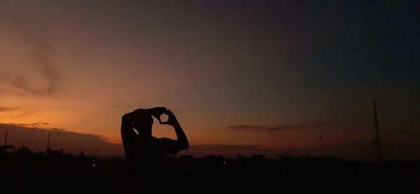 Silhouette man photographing against sky during sunset