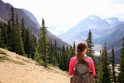 Rear view of female hiker standing against mountains
