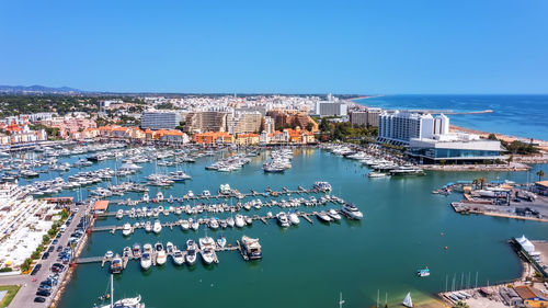 High angle view of city by sea against clear blue sky