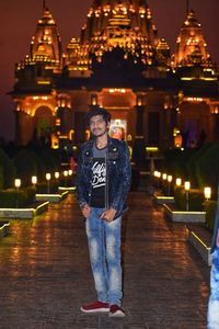 Portrait of man standing against illuminated city at night