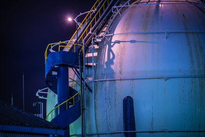 Low angle view of illuminated industry against sky at night