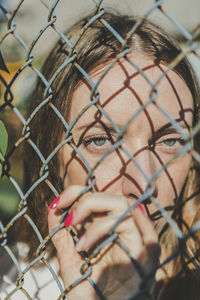 Close-up. the face of a young girl behind a metal fence