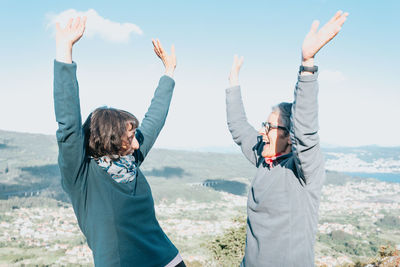 Rear view of woman with arms raised against sky