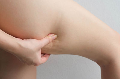 Cropped image of woman pinching thigh