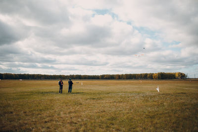 Men standing on field against sky